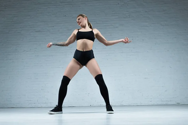 Tatoué sexy blonde fille en tenue noire dansant en studio — Photo de stock