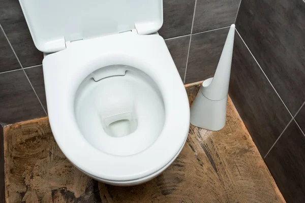 Ceramic clean toilet bowl in modern restroom with grey tile and toilet brush — Stock Photo