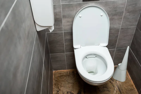 Cuvette de toilette propre en céramique dans les toilettes modernes avec carrelage gris et brosse de toilette — Photo de stock