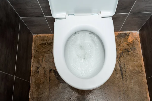 Керамическая чистая унитаз с смывом в современном туалете с серой плиткой — стоковое фото