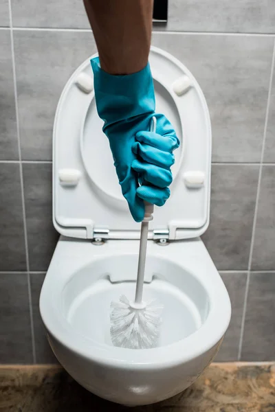 Vue recadrée du nettoyage nettoyant cuvette de toilette en céramique avec brosse de toilette dans les toilettes modernes avec tuile grise — Photo de stock