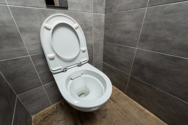 Ceramic clean toilet bowl in modern restroom with grey tile — Stock Photo