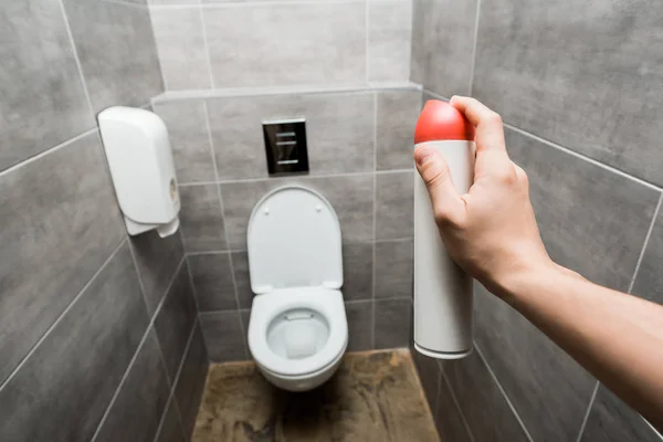 Cropped view of man holding air freshener in modern restroom with grey tile — Stock Photo