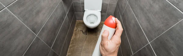 Cropped view of man spraying air freshener in modern restroom with grey tile — Stock Photo