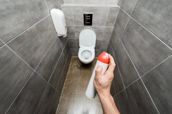 Cropped view of man spraying air freshener in modern restroom with grey tile — Stock Photo