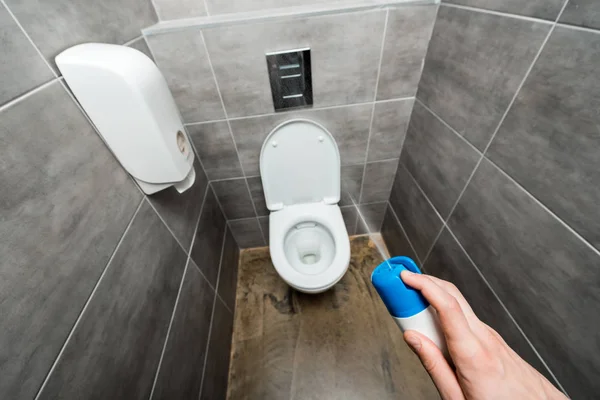 Cropped view of man spraying air freshener in modern restroom with grey tile — Stock Photo