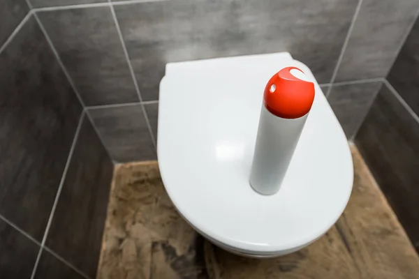 Air freshener in spray bottle on ceramic clean toilet bowl in modern restroom with grey tile — Stock Photo