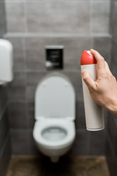 Abgeschnittene Ansicht eines Mannes, der Lufterfrischer in einer modernen Toilette mit grauer Fliese versprüht — Stockfoto