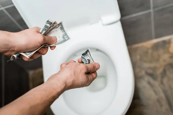Vue recadrée de l'homme jetant des billets en dollars dans un bol de toilette — Photo de stock