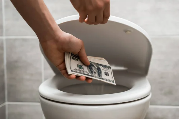 Vista cortada de homem jogando notas de dólar em vaso sanitário — Fotografia de Stock