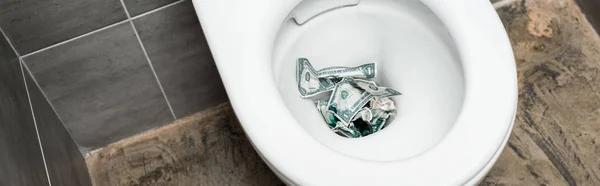 Dollarnoten in Toilettenschüssel in moderner Toilette mit grauer Fliese, Panoramaaufnahme — Stockfoto