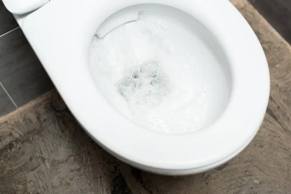Чистая белая унитаз с смывом в современном туалете с серой плиткой — стоковое фото