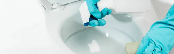Vista recortada del hombre en guantes de goma limpiador inodoro con detergente y esponja aislado en blanco, tiro panorámico - foto de stock