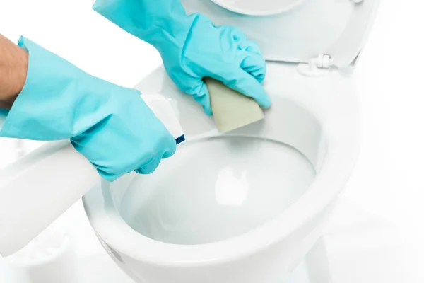 Ausgeschnittene Ansicht eines Mannes in Gummihandschuhen, der Toilettenschüssel mit Waschmittel und Schwamm auf Weiß reinigt — Stockfoto