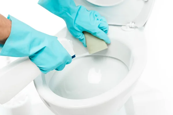 Vista recortada del hombre en guantes de goma limpiador inodoro con detergente y esponja en blanco - foto de stock