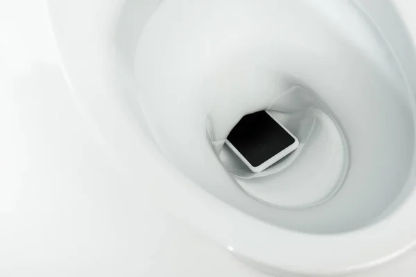 Vue rapprochée du smartphone dans un bol de toilette en céramique propre isolé sur blanc — Photo de stock