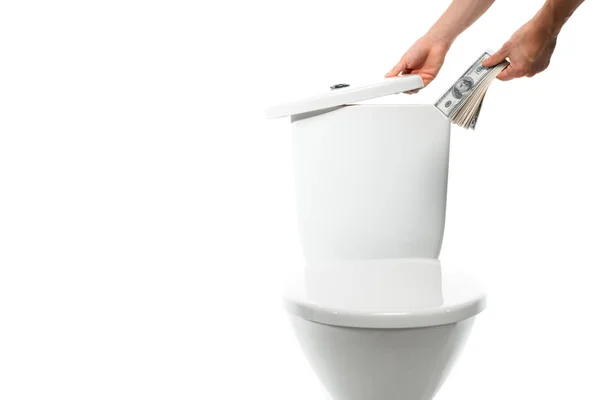 Vista cortada de mulher escondendo dólares em cerâmica vaso sanitário limpo isolado em branco — Fotografia de Stock