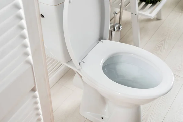 Banheiro moderno branco com vaso sanitário perto da tela dobrável — Fotografia de Stock