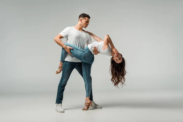 Tänzer in T-Shirts und Jeans tanzen Bachata auf grauem Hintergrund — Stockfoto