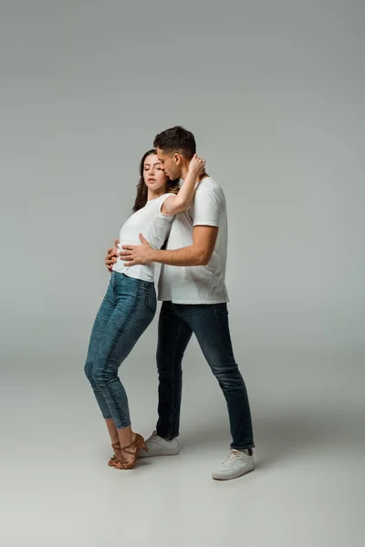 Dancers in t-shirts and jeans dancing bachata on grey background — Stock Photo