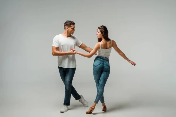 Танцюристи в джинсах танцюють баната на сірому фоні — Stock Photo