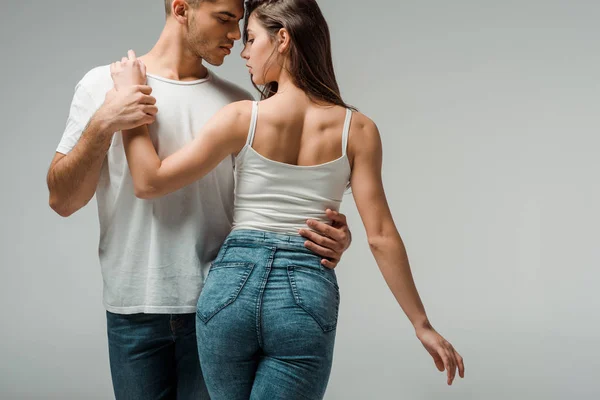 Танцоры в джинсах в джинсах танцующие бачата изолированные на сером — стоковое фото