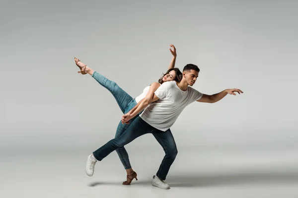 Tänzer mit geschlossenen Augen tanzen Bachata auf grauem Hintergrund — Stockfoto