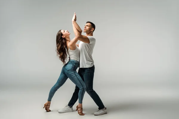 Bailarinos olhando para cima e dançando bachata em fundo cinza — Fotografia de Stock