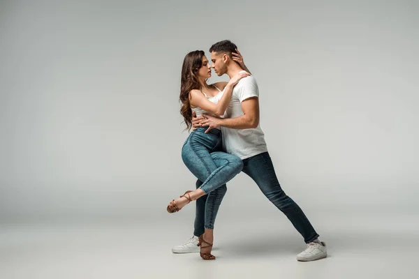 Bailarinos de jeans jeans dançando bachata em fundo cinza — Fotografia de Stock