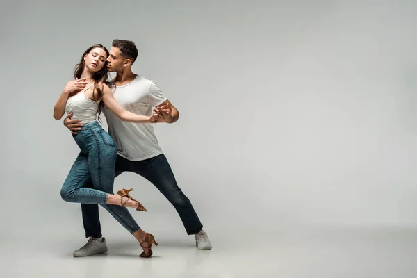 Dancers in denim jeans dancing bachata on grey background — Stock Photo