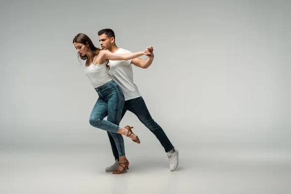 Tänzer in Jeans tanzen Bachata auf grauem Hintergrund — Stockfoto