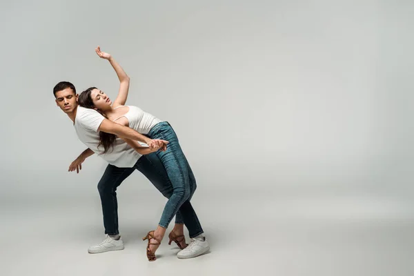 Tänzer mit geschlossenen Augen tanzen Bachata auf grauem Hintergrund — Stockfoto