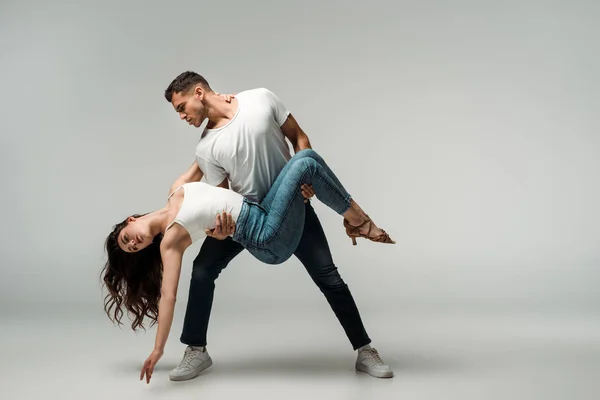 Dancers in denim jeans dancing bachata on grey background — Stock Photo