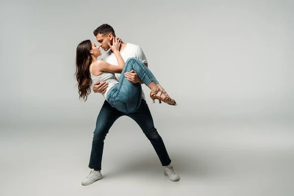 Bailarinos de jeans jeans dançando bachata em fundo cinza — Fotografia de Stock