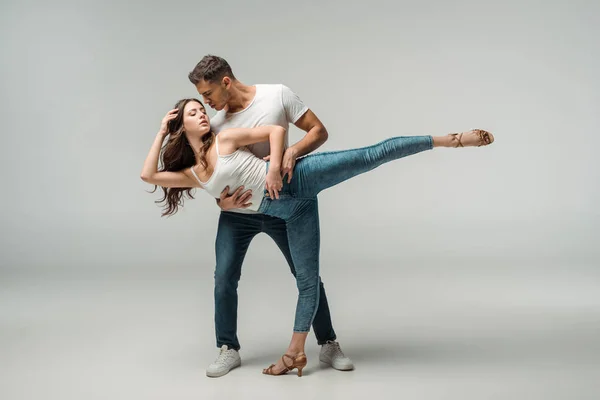 Ballerini in jeans jeans danza bachata su sfondo grigio — Foto stock