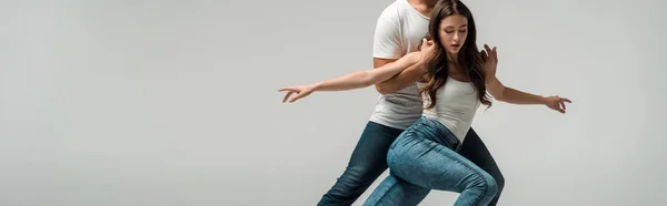 Plano panorámico de bailarinas en vaqueros bailando bachata aisladas en gris - foto de stock