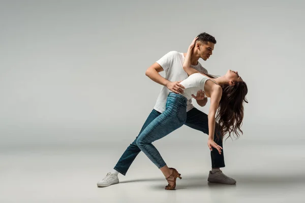 Tänzer in Jeans tanzen Bachata auf grauem Hintergrund — Stockfoto