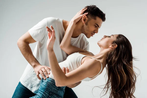 Bailarines bailando bachata y mirándose aislados en gris - foto de stock