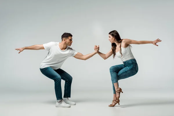 Vue latérale des danseurs en jeans denim dansant bachata sur fond gris — Photo de stock