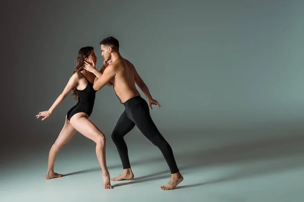 Вид збоку сексуальних танцюристів, які танцюють сучасні на темному фоні — стокове фото