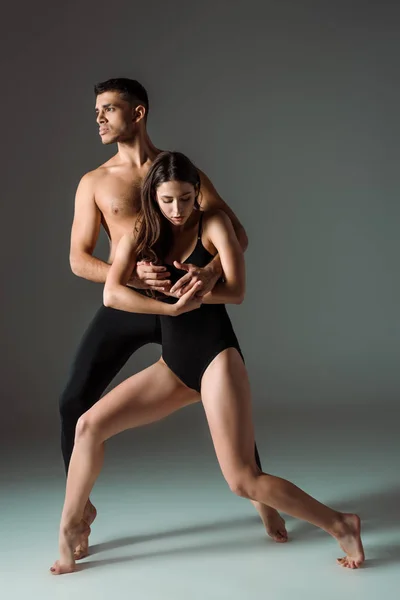 Danseurs attrayants et beaux dansant contemporain sur fond sombre — Photo de stock