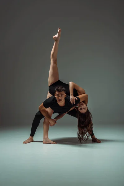 Gut aussehende und attraktive Tänzer, die zeitgenössisch auf dunklem Hintergrund tanzen — Stockfoto