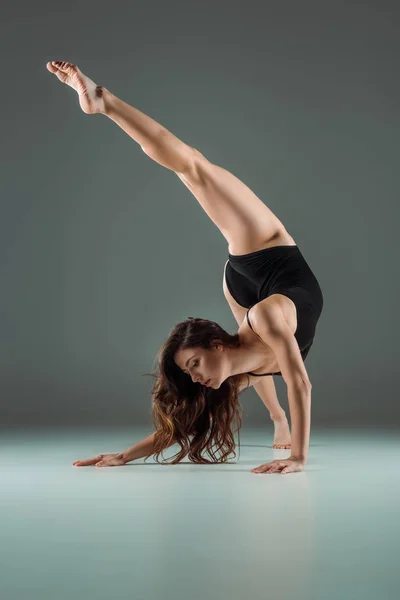 Attraktive Tänzerin im schwarzen Body, die zeitgenössisch auf dunklem Hintergrund tanzt — Stockfoto