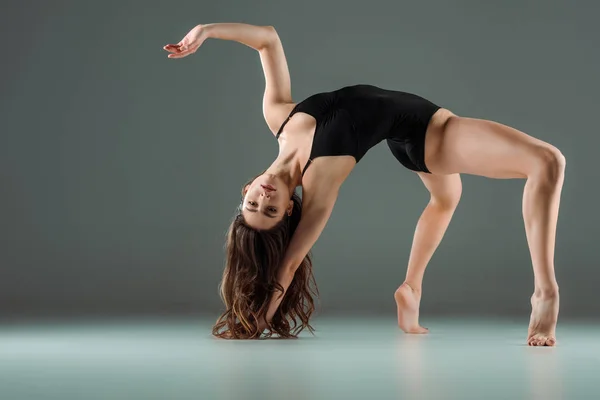 Atractiva bailarina de body negro bailando contemporáneo sobre fondo oscuro - foto de stock