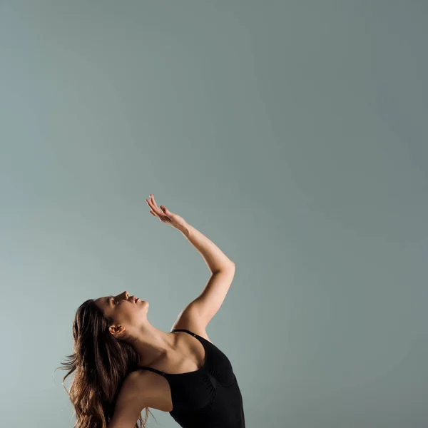 Приваблива танцівниця в чорному костюмі танцює сучасно ізольовано на сірому — стокове фото