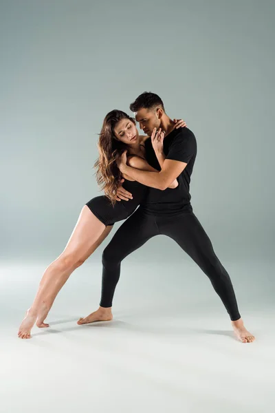 Bailarines con los ojos cerrados bailando contemporáneo sobre fondo gris - foto de stock