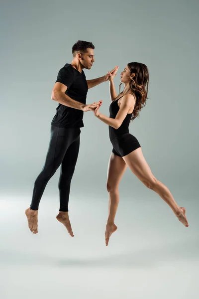 Bailarines guapos y atractivos bailando contemporáneo sobre fondo gris - foto de stock