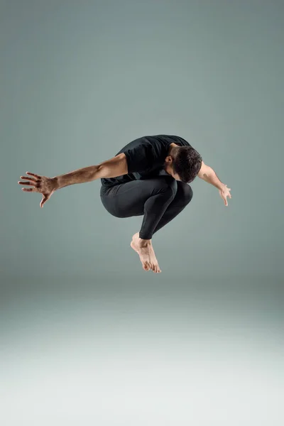 Tänzer in schwarzen Leggings und T-Shirt tanzen zeitgenössisch auf dunklem Hintergrund — Stockfoto