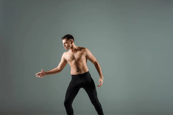 Handsome dancer in black leggings dancing contemporary isolated on grey — Stock Photo