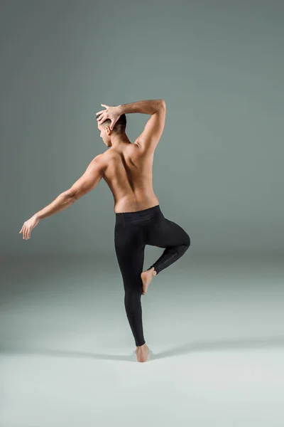 Vue arrière du danseur en legging noir dansant contemporain sur fond sombre — Photo de stock